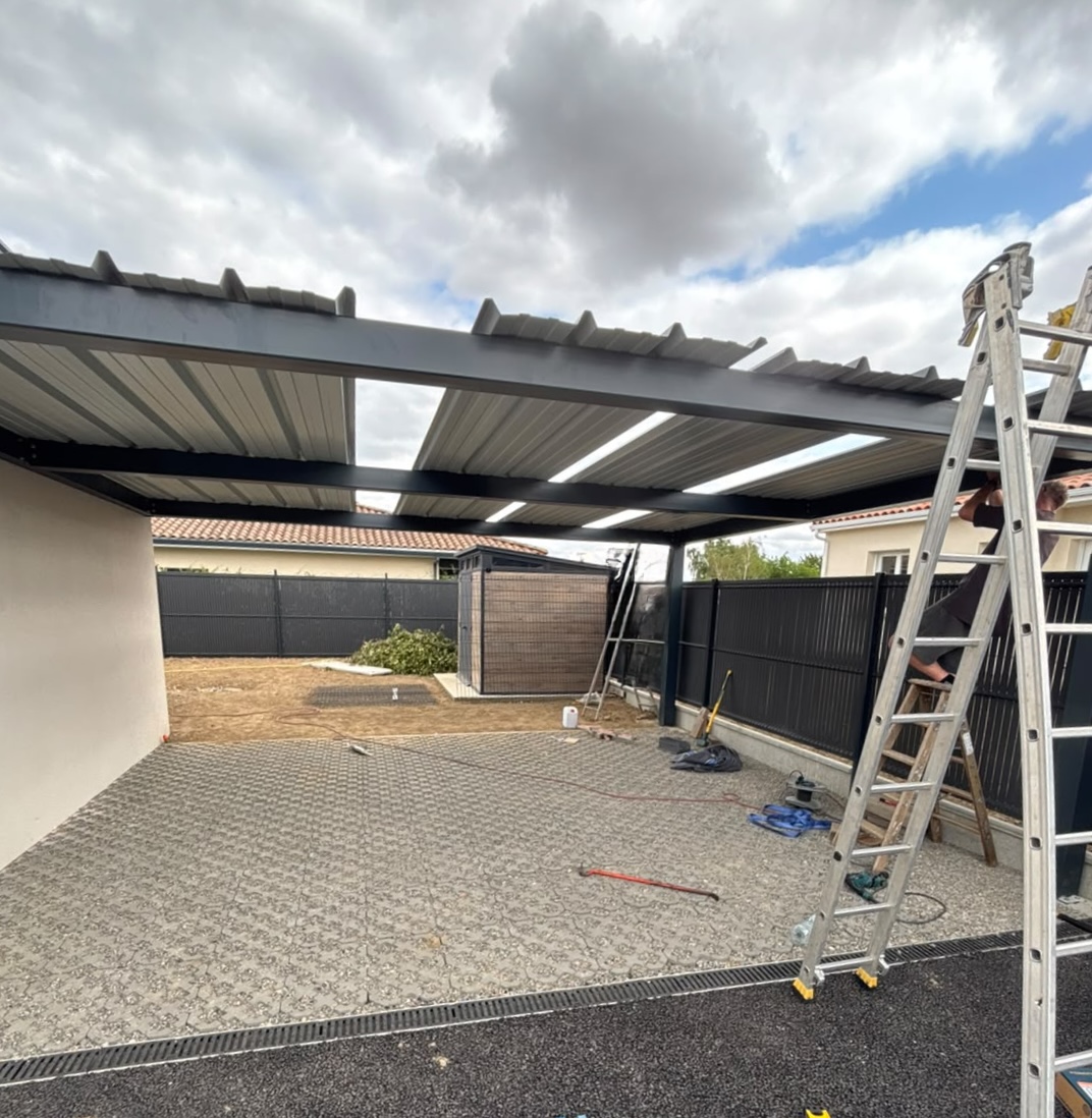 Carport en acier adossé à une maison, photographié pendant la pose