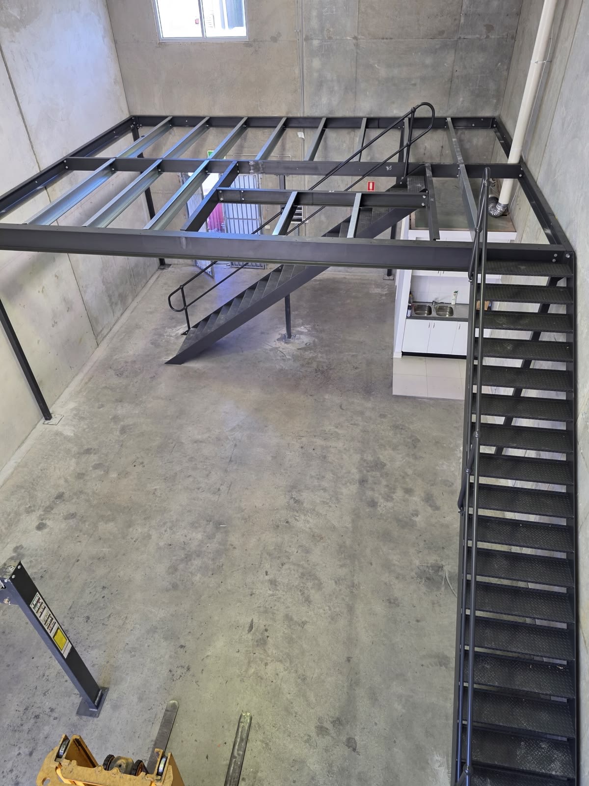 Ossature de mezzanine métallique et escalier en cours d'installation
